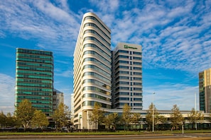Een modern hotel met een gebogen gevel, meerdere verdiepingen en een opvallend logo aan de zijkant.