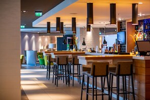 A modern bar area with high stools, a counter, and hanging pendant lights.