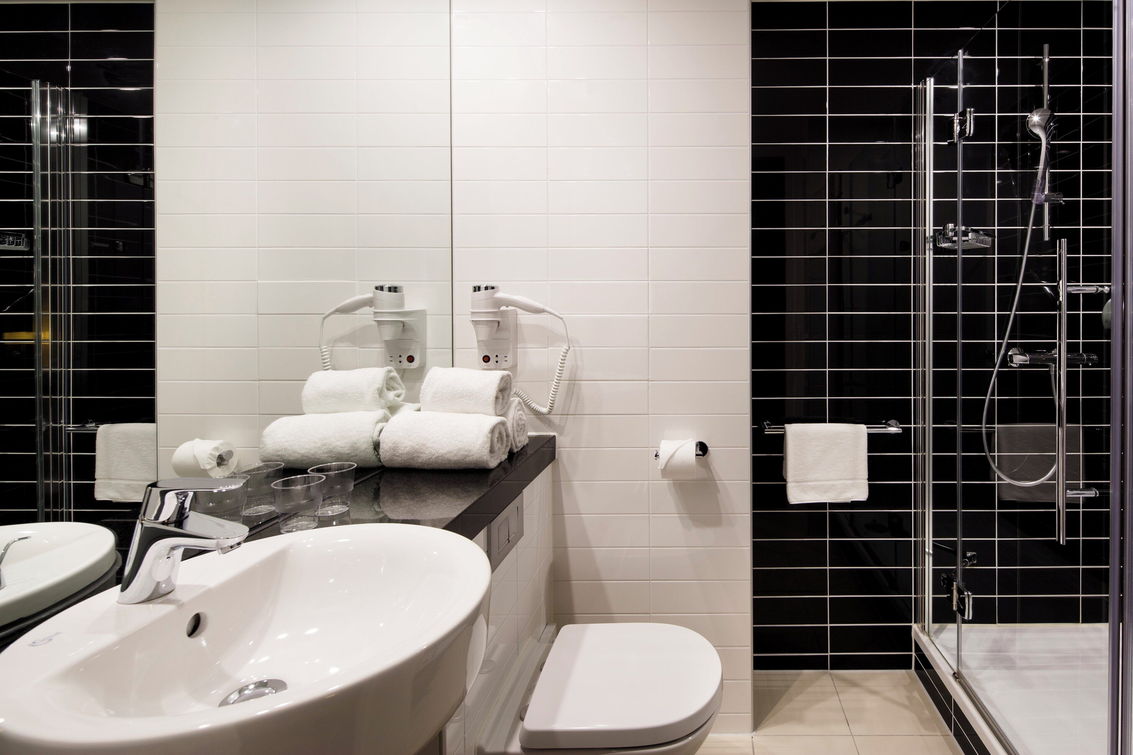 Une salle de bain moderne avec un lavabo blanc, des toilettes et une douche séparée par une paroi de verre.