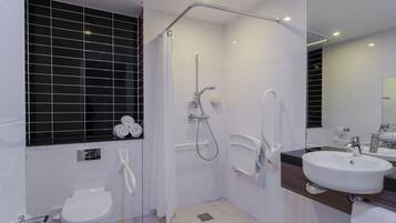 Een moderne badkamer met douche, toilet en wastafel.