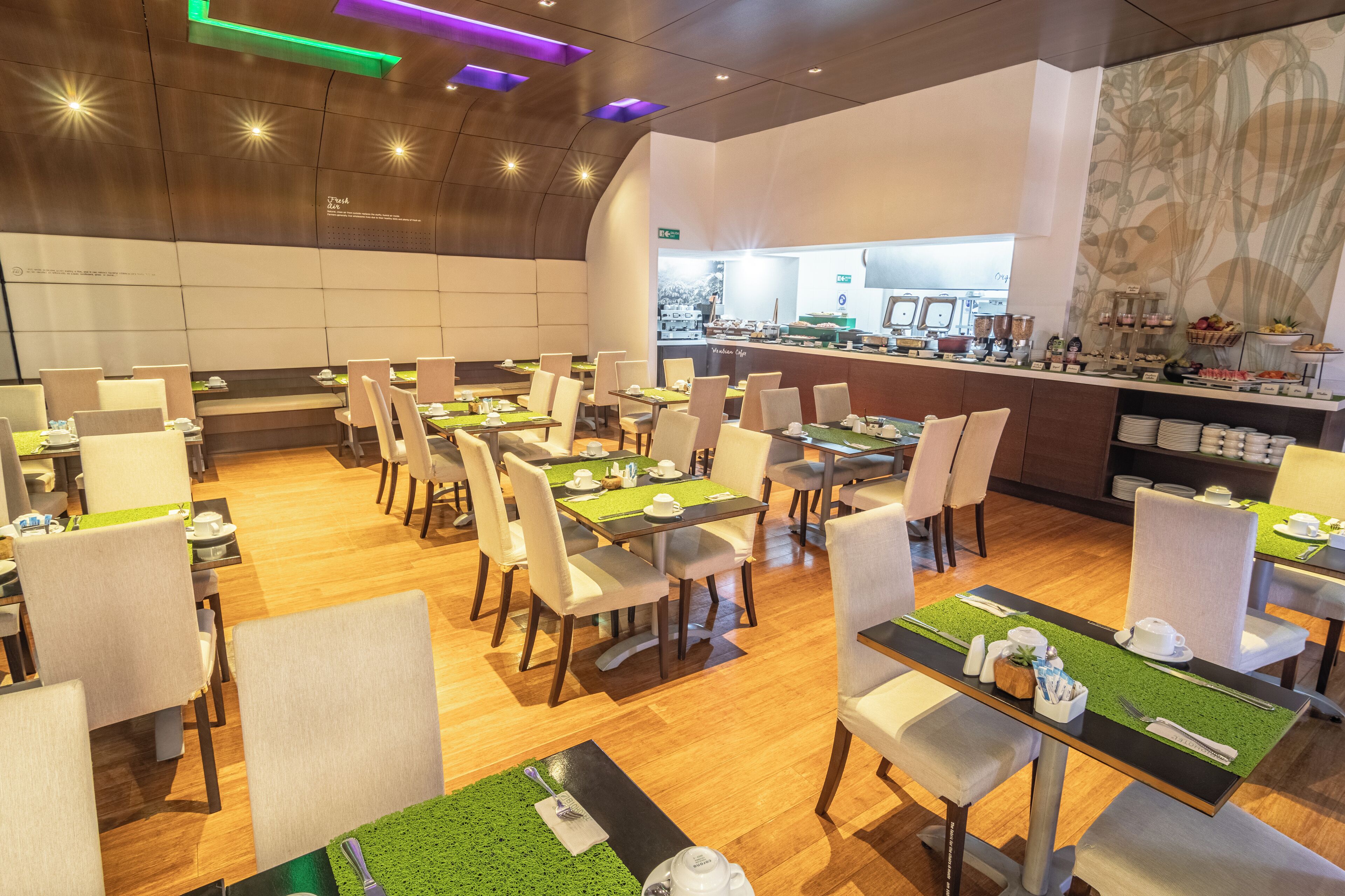Un restaurante con varias mesas, sillas y una zona de cocina al fondo.