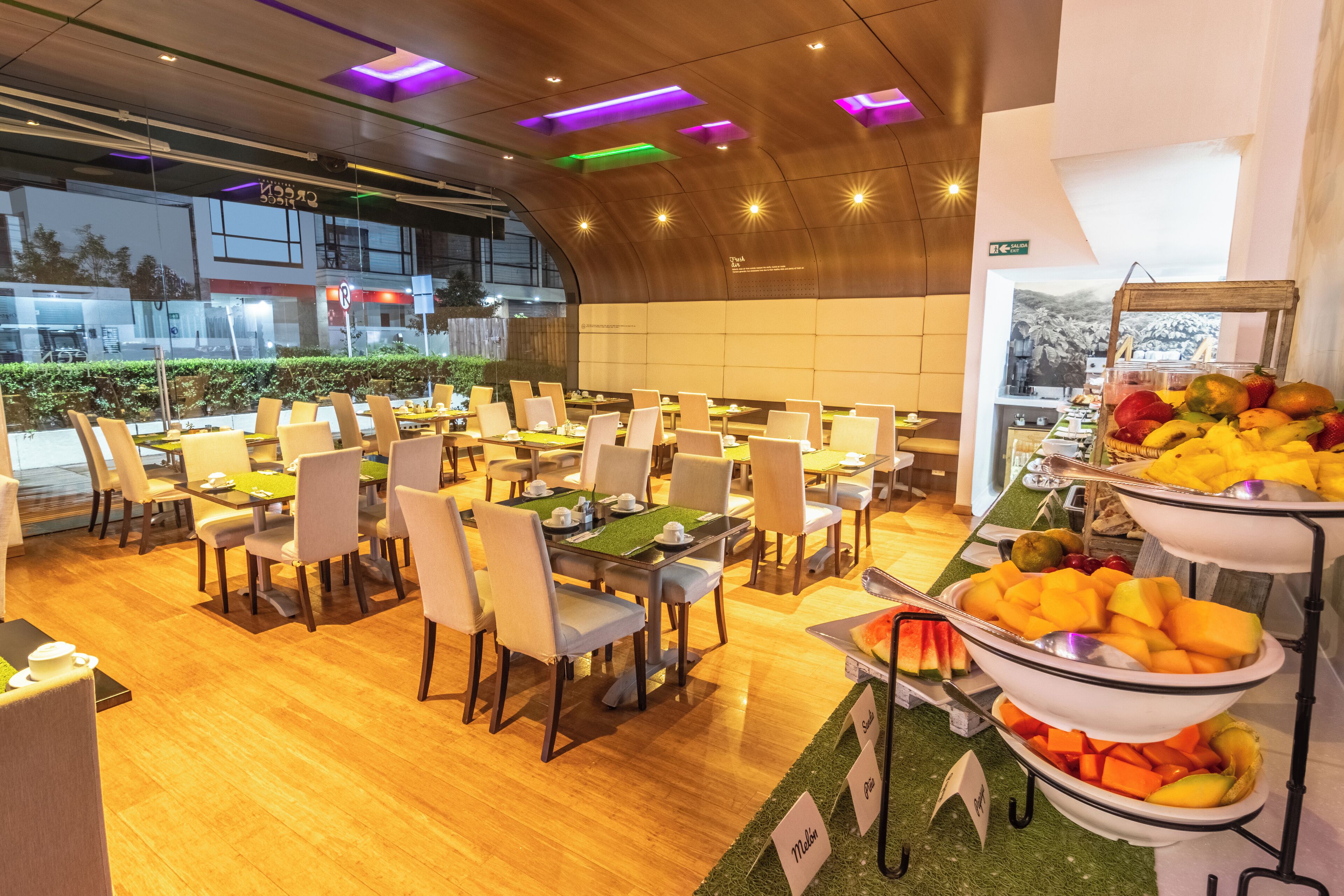 A dining area with multiple tables and chairs, a fruit display, and a view of the outdoors.
