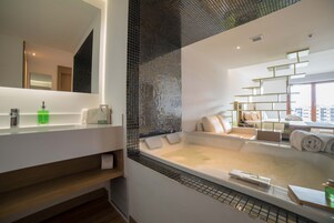 A modern bathroom with a large bathtub, a mirror, and a shelf with toiletries.