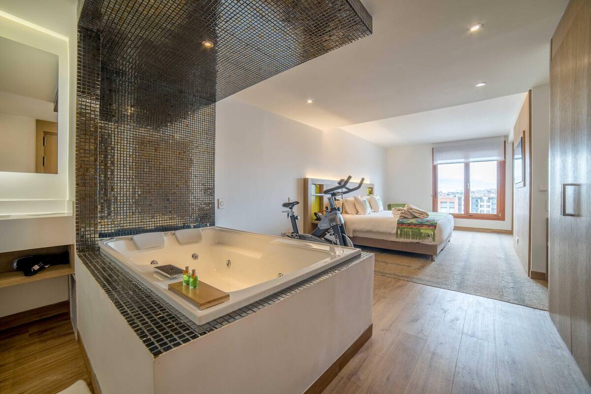 A modern bathroom with a large bathtub, a shower area, and a mirror.