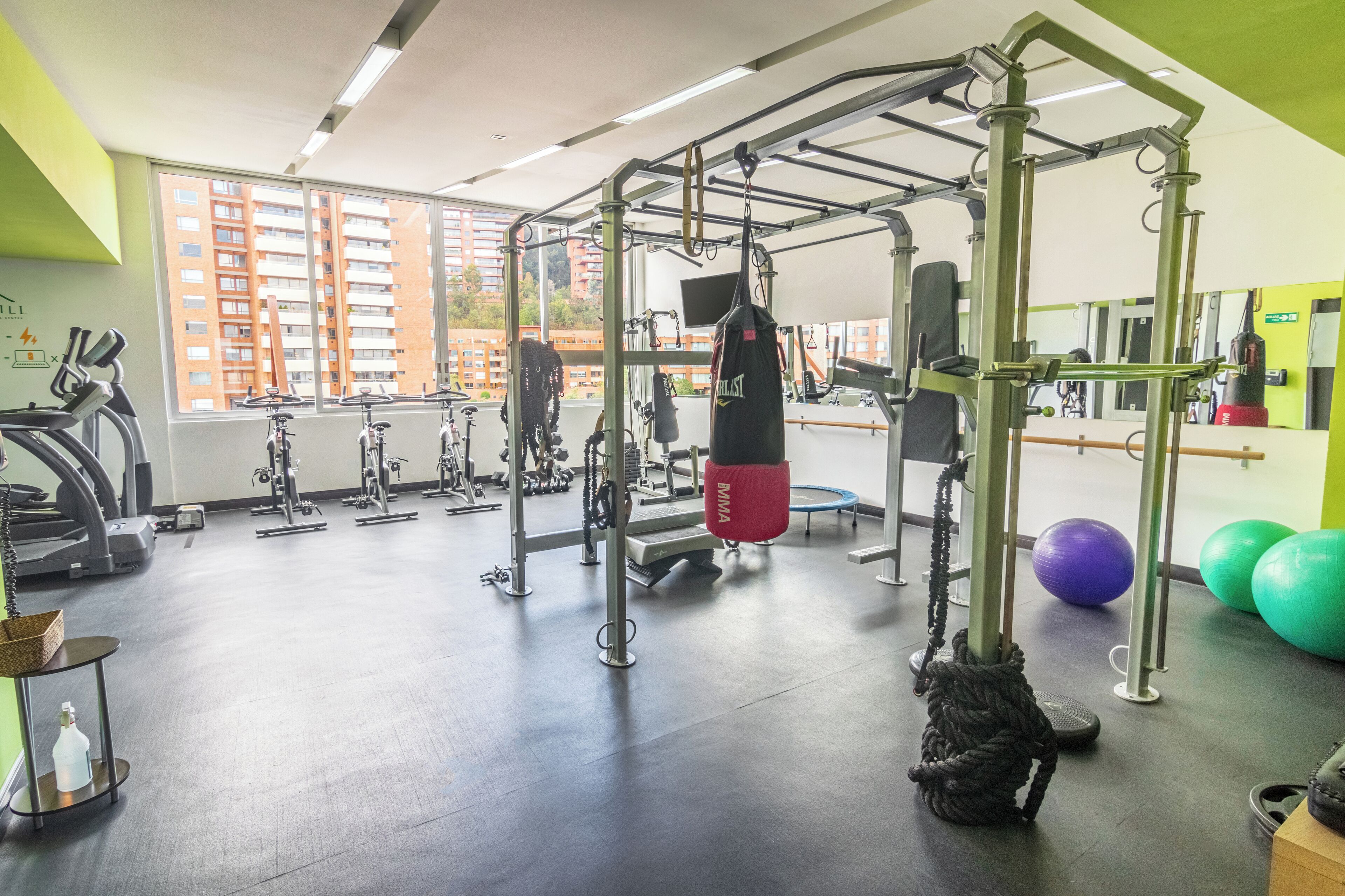 Un gimnasio con equipo de ejercicio, saco de boxeo y pelotas de fitness.