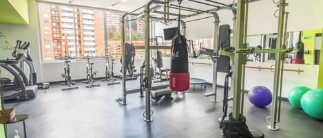Un gimnasio con equipo de ejercicio, saco de boxeo y pelotas de fitness.