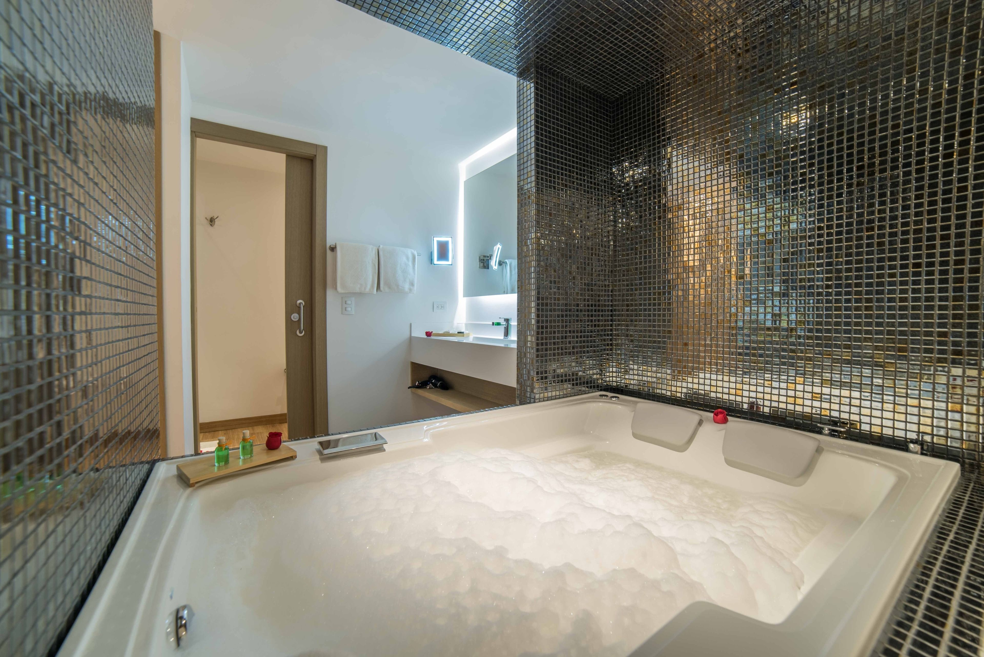 Un baño moderno con una bañera grande, zona de ducha y un espejo con luz.