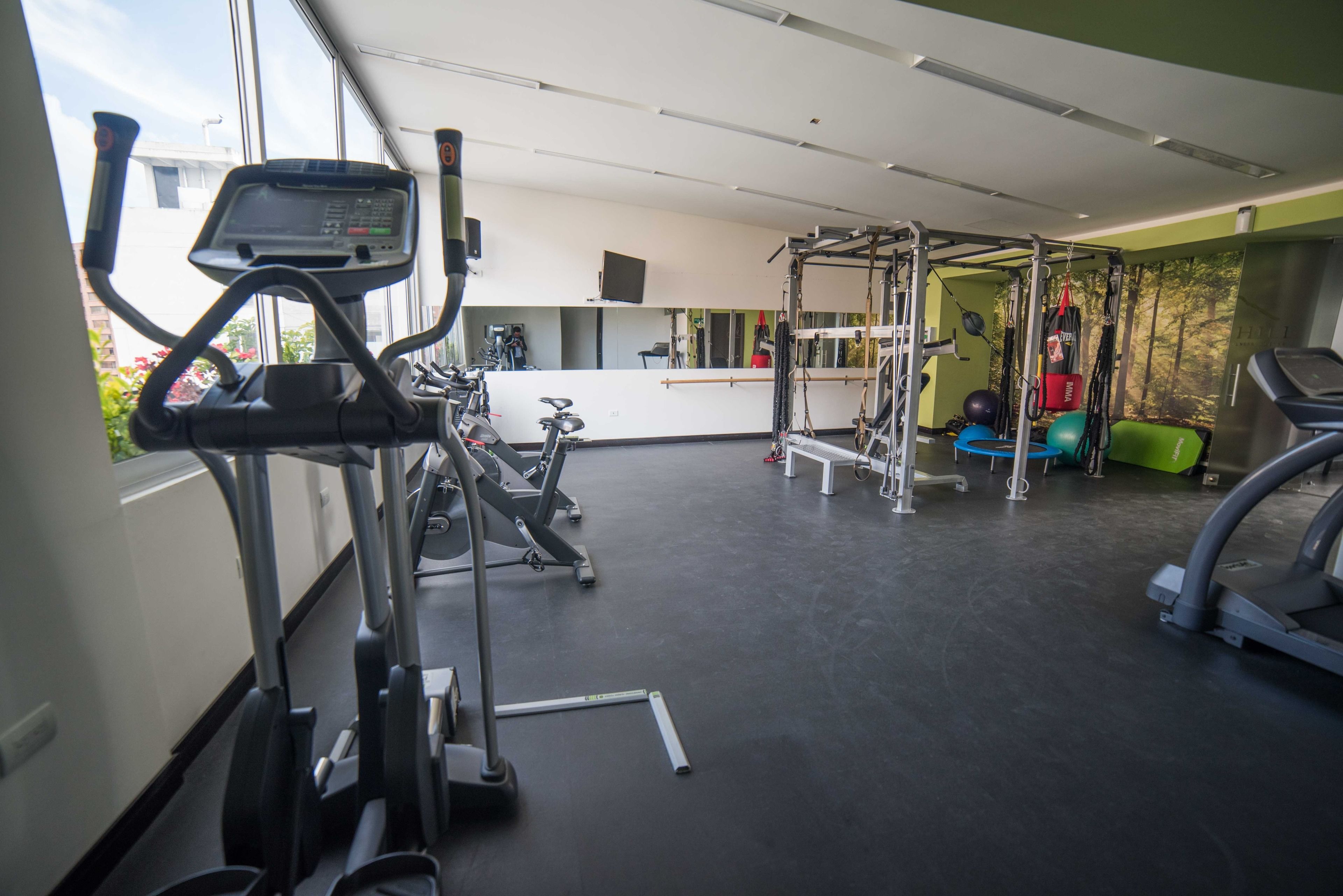 Une salle de sport équipée de tapis de course, de vélos d’exercice et d’un espace dédié à la musculation.