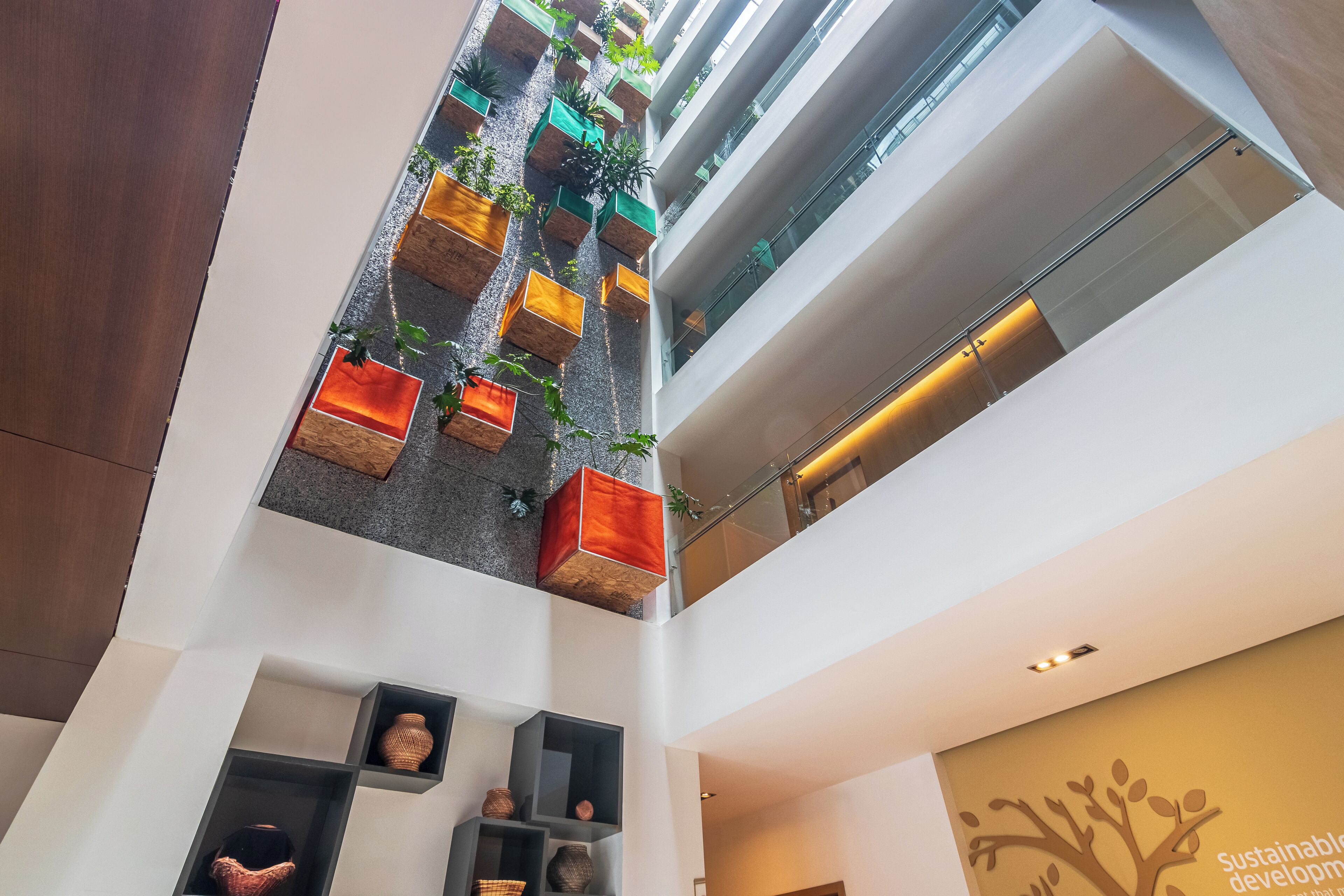 A modern atrium with a central planter wall, glass railings, and a visible ceiling.