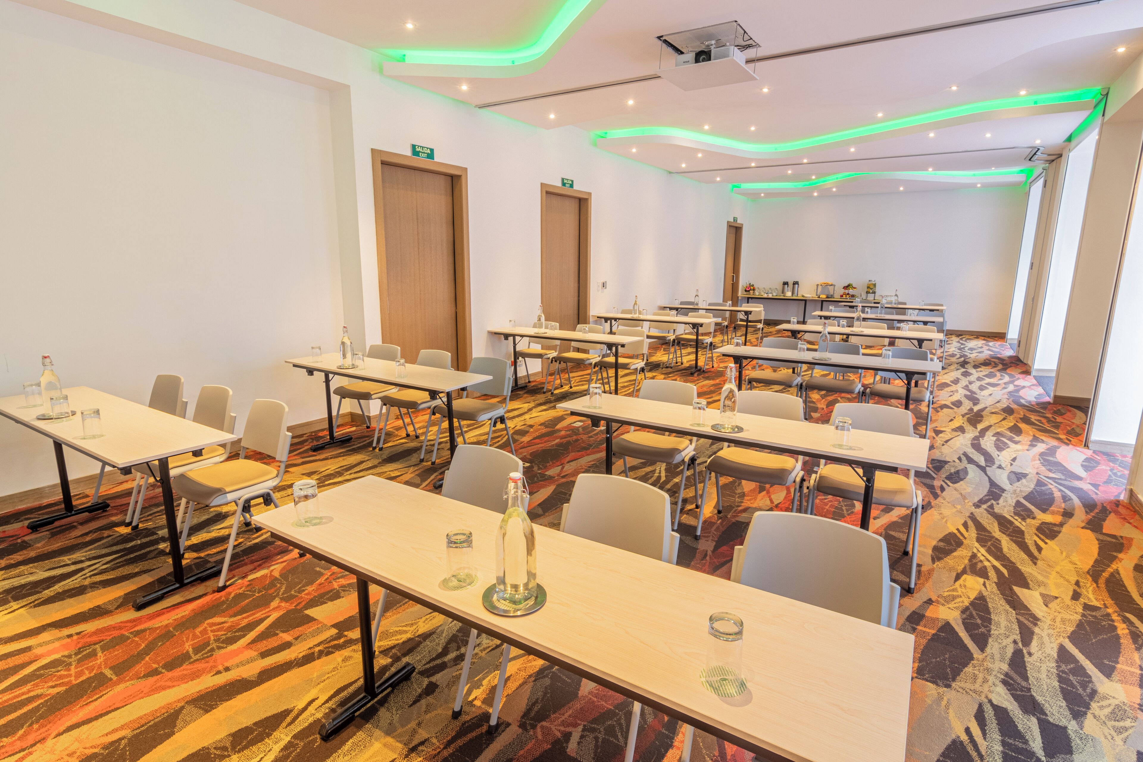 A conference room with multiple tables and chairs, equipped with nameplates and water bottles.