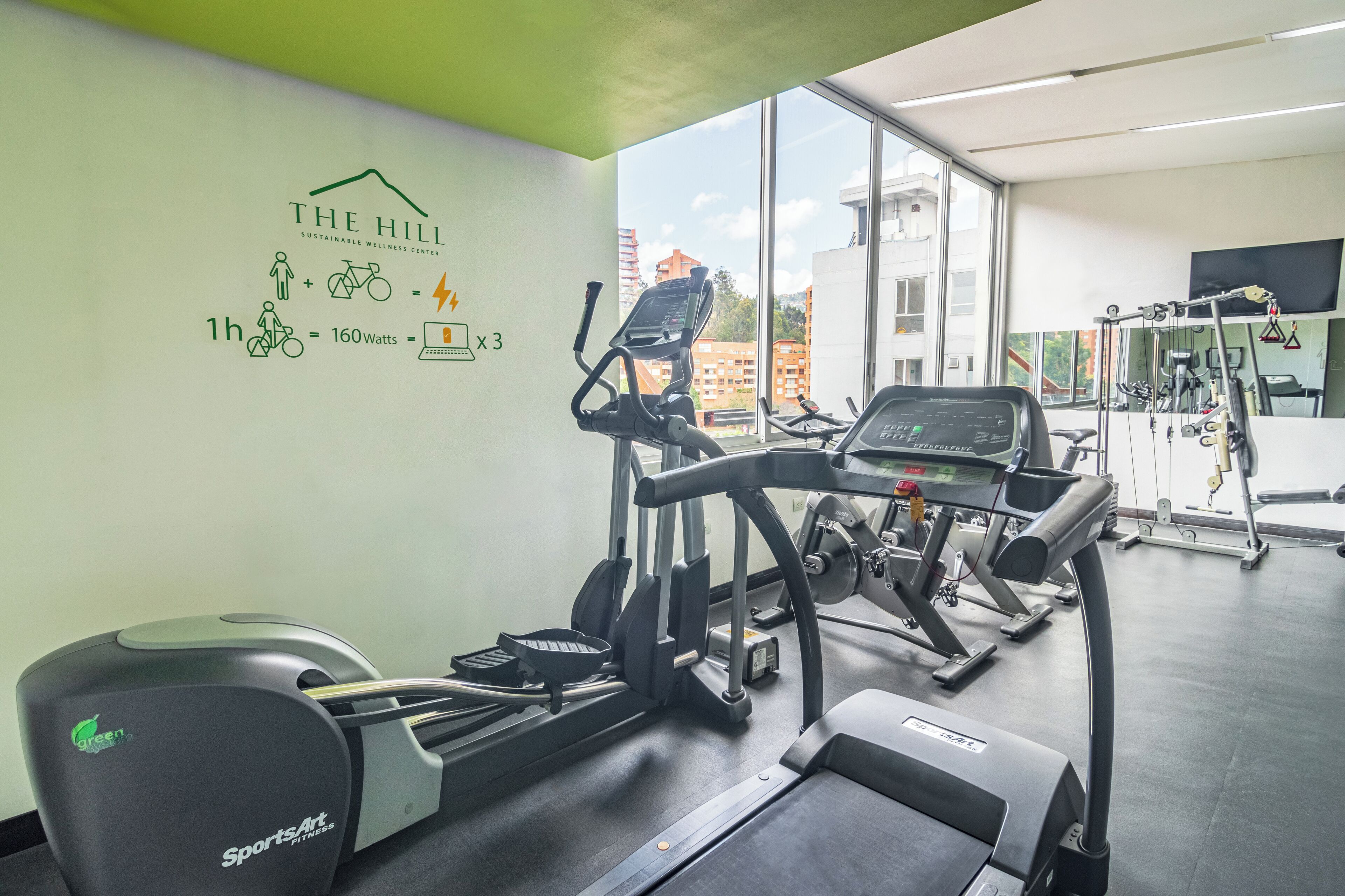 Una palestra con tapis roulant, biciclette cardiologiche e macchinari per l'allenamento della forza.