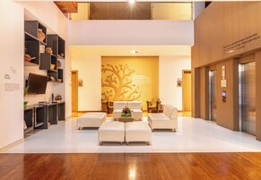 Un lobby moderno con una zona de estar central, una pared con diseño de árbol y suelo de madera.