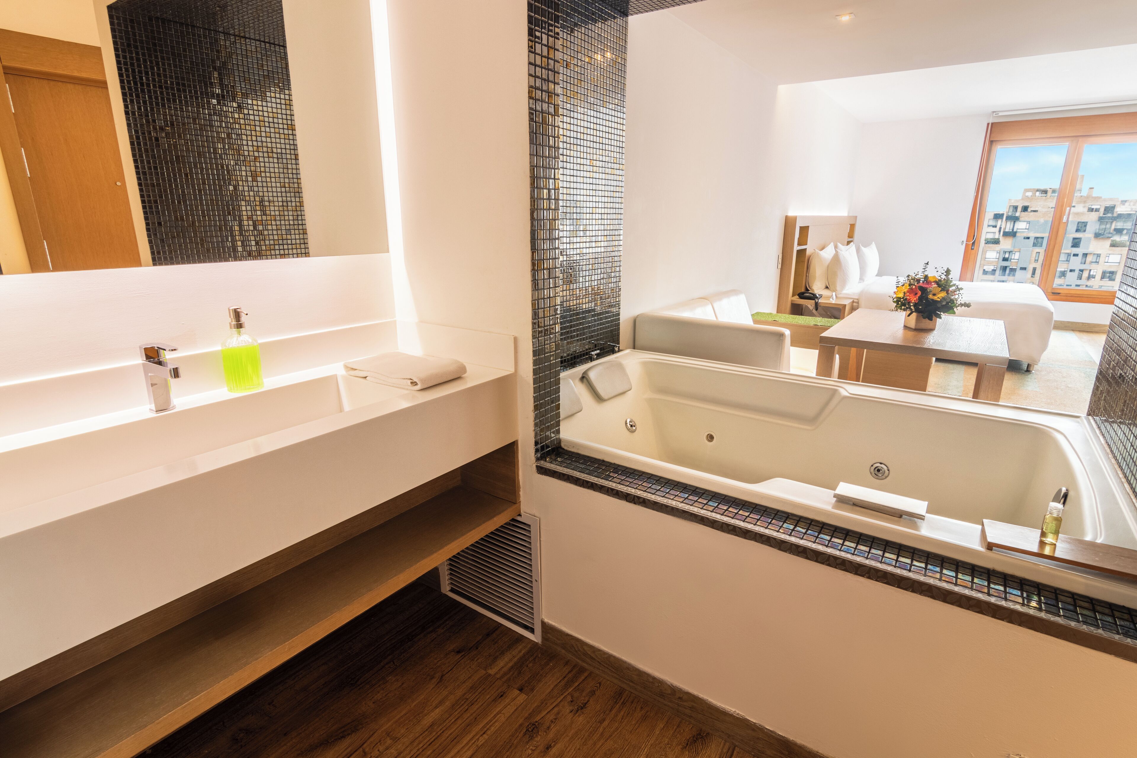 A modern bathroom with a large bathtub, a separate shower area, and a vanity with a mirror.