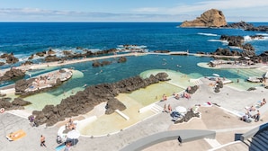 Un complejo turístico en la costa con aguas cristalinas, formaciones rocosas y una zona de playa arenosa.