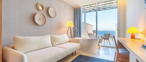 A modern living room with a sofa, coffee table, and lamps. There is a balcony with a view.