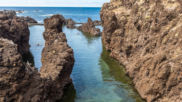 Zona costera rocosa con aguas claras y un buceador.