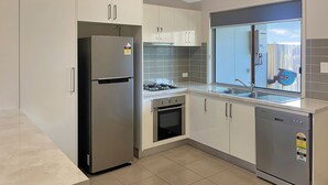 Una cocina moderna con armarios blancos, electrodomésticos de acero inoxidable, horno integrado y lavavajillas.