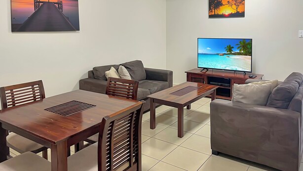 Una sala de estar con una mesa de comedor de madera, dos sofás, un televisor y obras de arte en las paredes.
