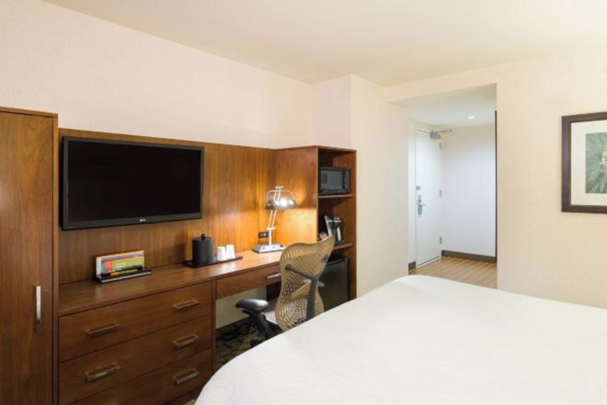 Une chambre d’hôtel équipée d’un lit, d’un bureau avec un ordinateur, d’une télévision et d’un four à micro-ondes.