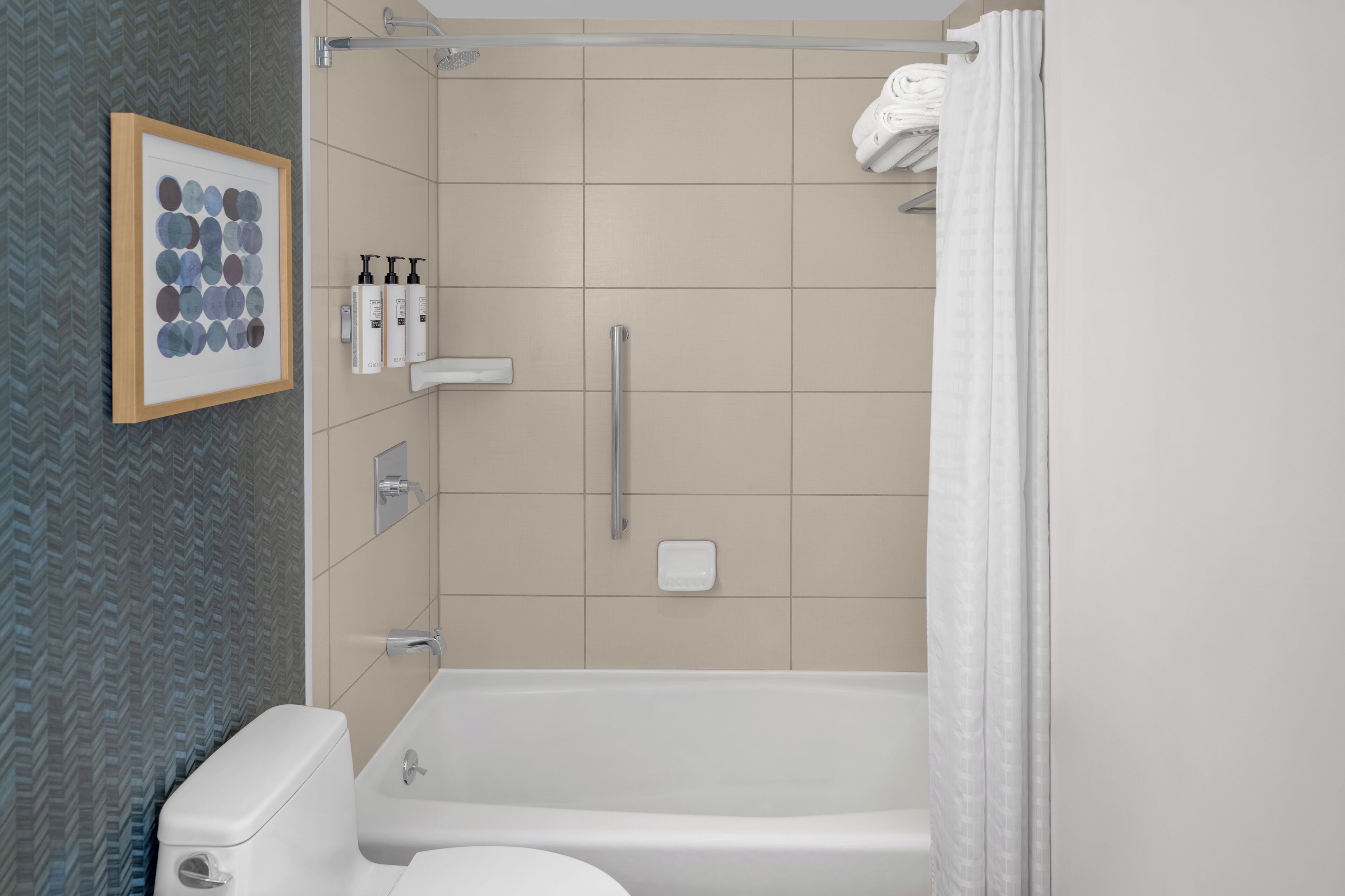 Ein modernes Badezimmer mit Dusche, Toilette und einem gerahmten Kunstwerk an der Wand.
