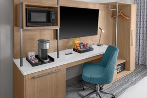 A modern hotel room with a wooden desk, a microwave, a coffee maker, a TV, and a wardrobe. - Hilton Garden Inn New York/Manhattan-Midtown East (New York)