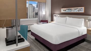 Een hotelkamer met een bed, een koffiezetapparaat, een raam met uitzicht op de stad, een schilderij aan de muur en een rode stoel.