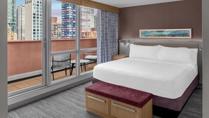Een hotelkamer met een groot bed, een houten bankje, een bijzettafeltje en een stoel.