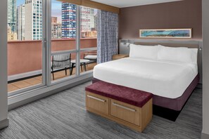 Ein Hotelzimmer mit einem großen Bett, einer Holzbank, einem kleinen Tisch und einem Stuhl.