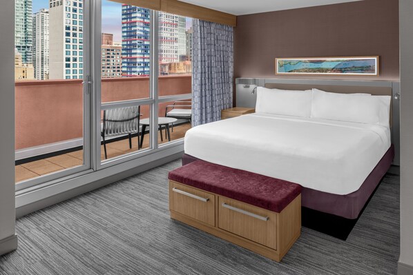 A hotel room with a large bed, a wooden bench, a small table, and a chair. - Hilton Garden Inn New York/Manhattan-Midtown East (New York)