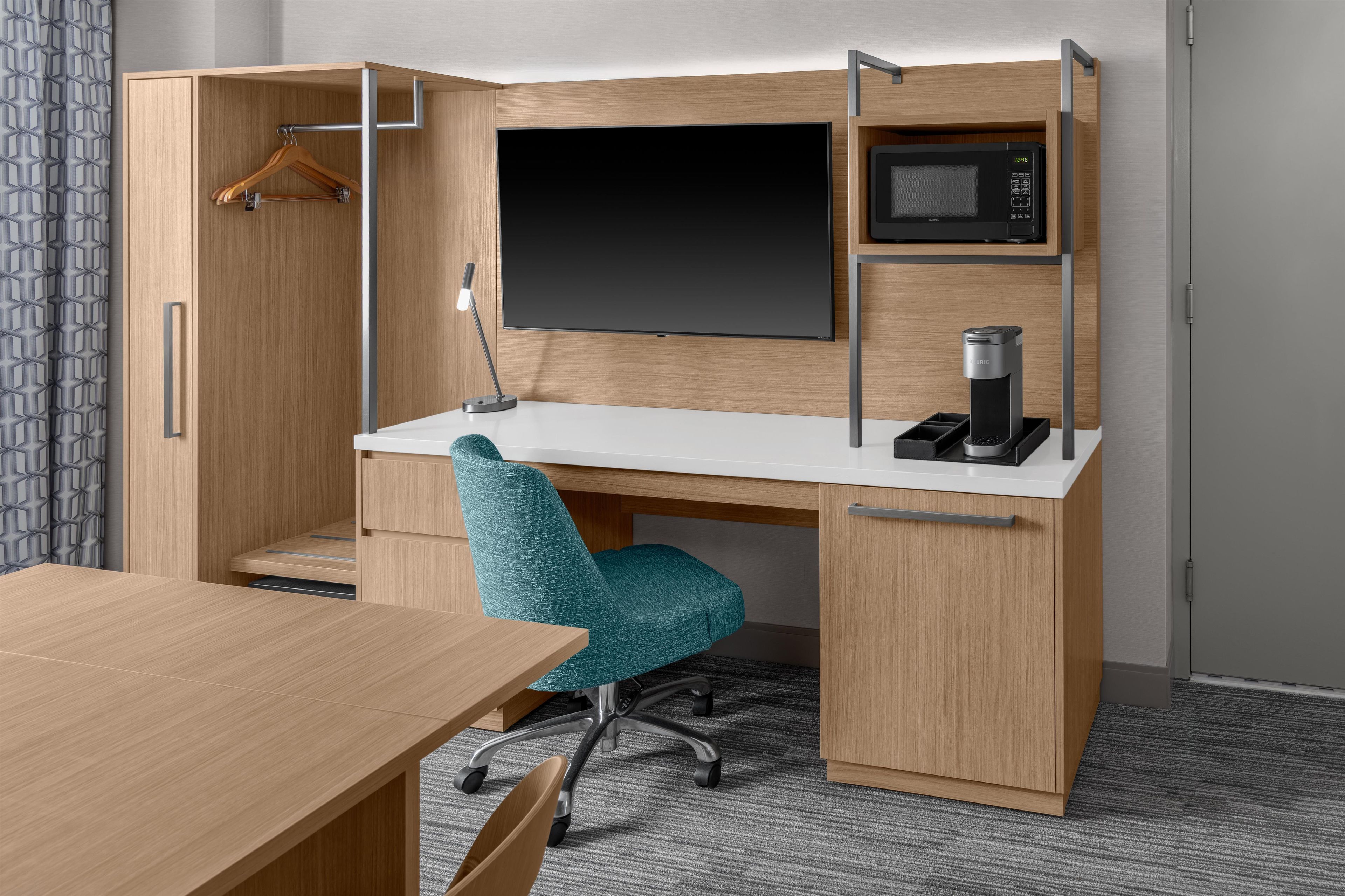 A compact office space with a desk, chair, and built-in microwave.