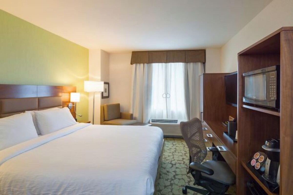 Une chambre d’hôtel équipée d’un lit, d’un bureau, d’une chaise, d’une télévision et d’un four à micro-ondes.