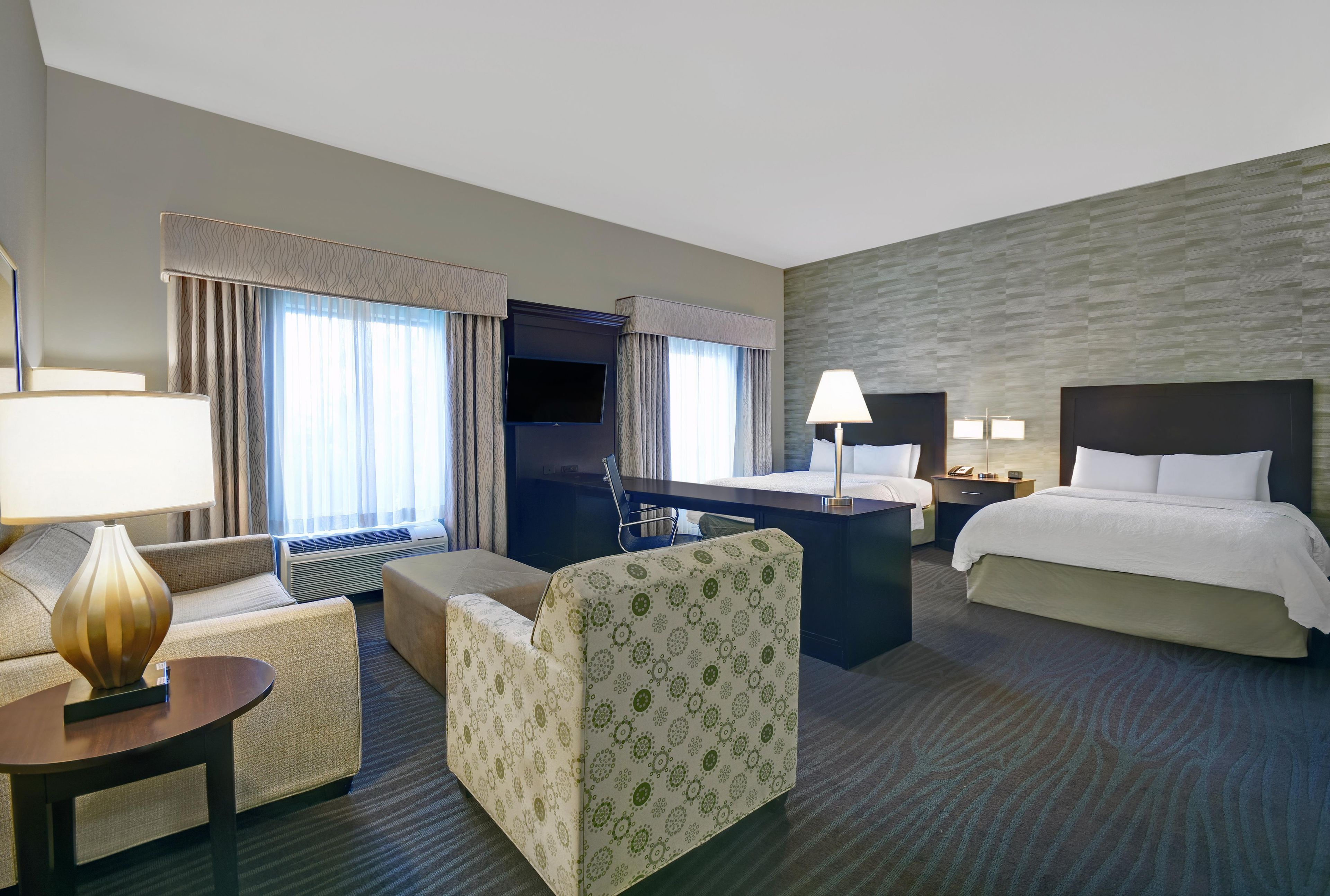 Une chambre d’hôtel avec un lit, un bureau, une chaise, un canapé et une lampe.