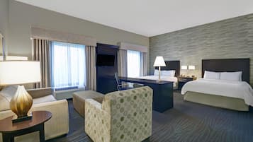 Une chambre d’hôtel avec un lit, un bureau, une chaise, un canapé et une lampe.