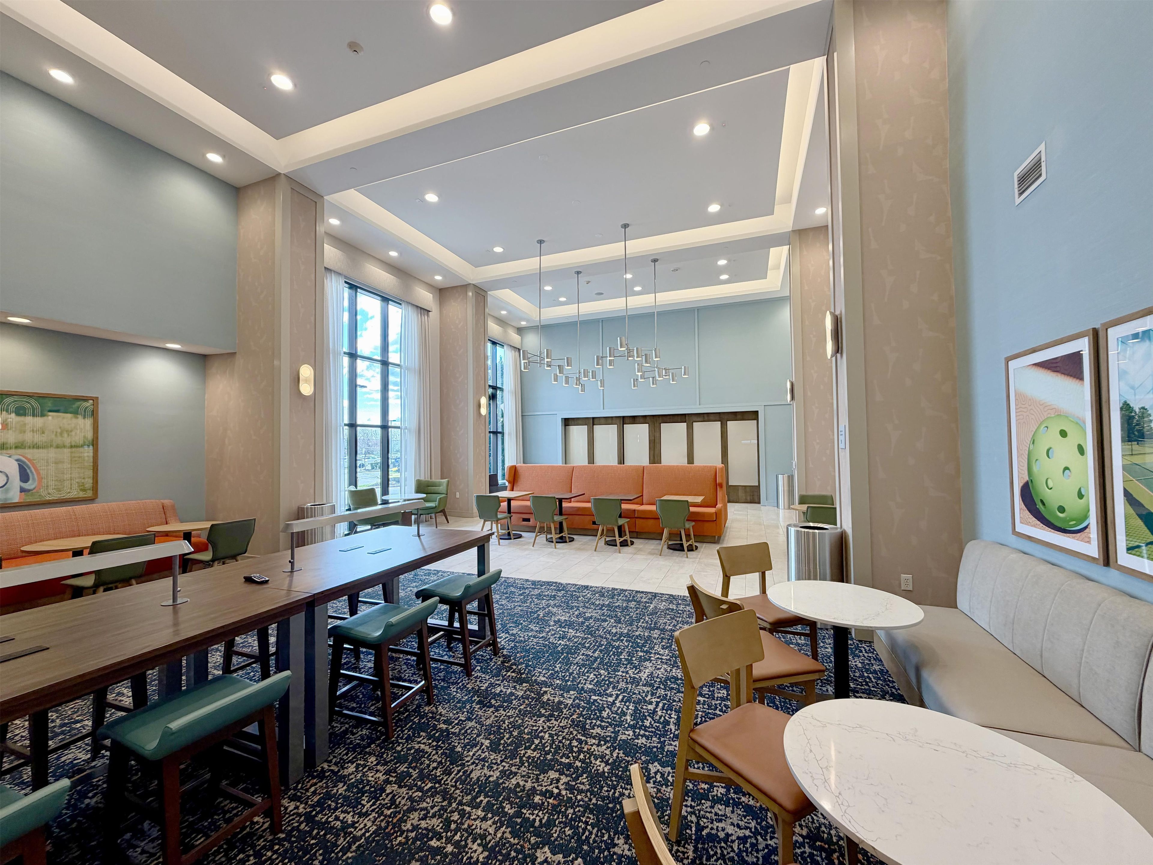 A spacious room with a long table, multiple chairs, a sofa, and a patterned carpet.