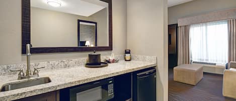 Un baño de hotel con lavamanos, espejo y microondas empotrado.