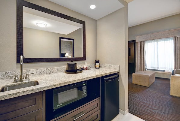 A hotel bathroom with a sink, mirror, and a built-in microwave.