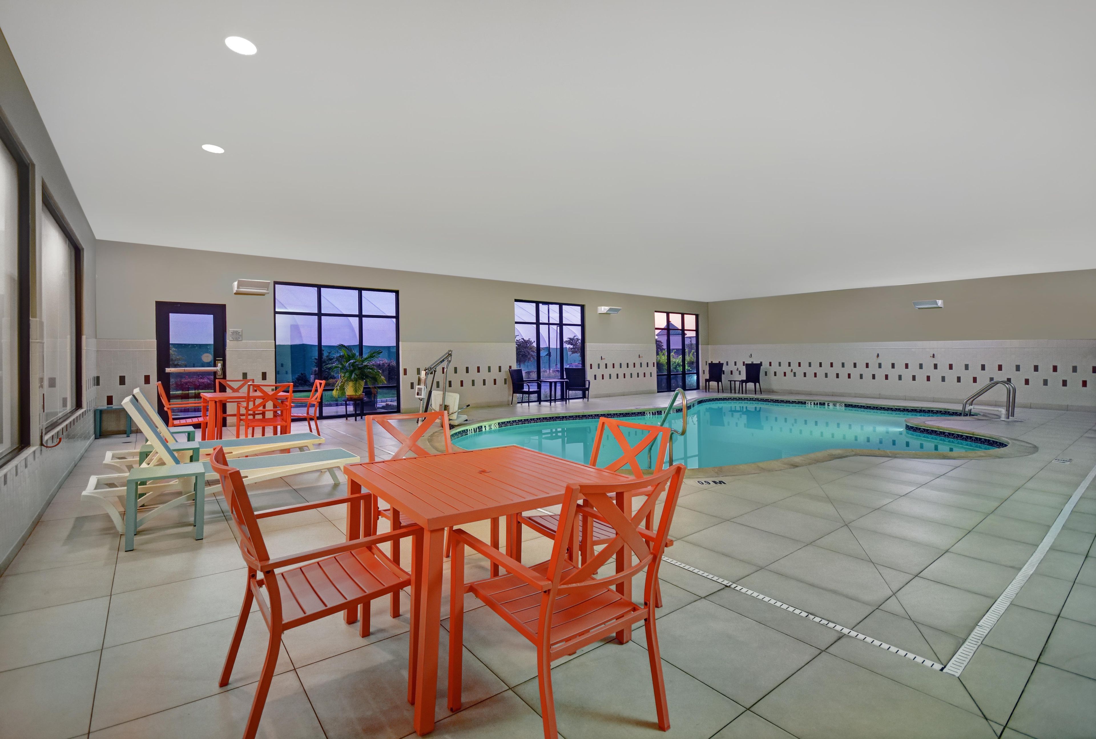 Zona de piscina con varias opciones de asientos y vistas al exterior a través de amplios ventanales.