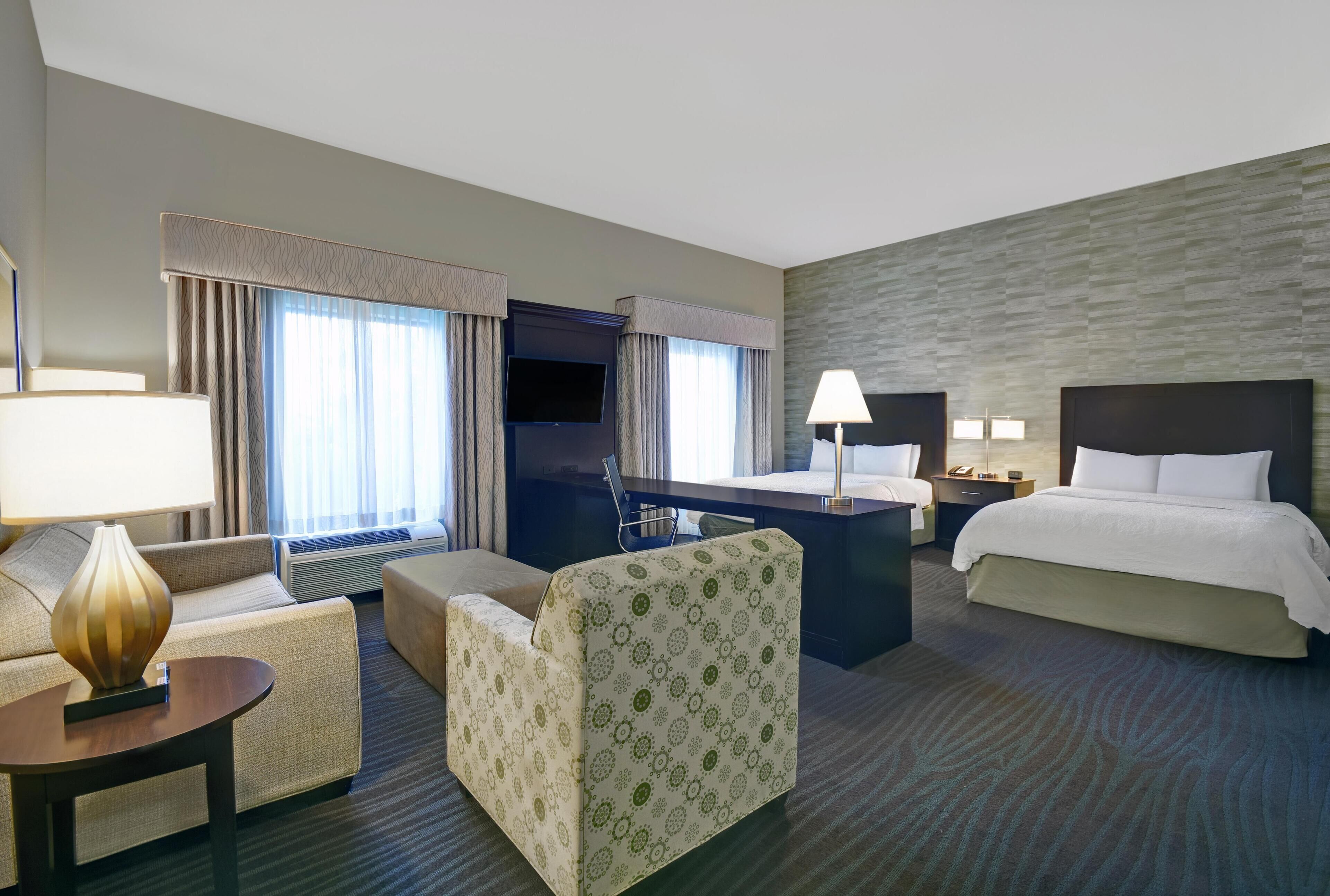 A hotel room with a bed, a desk, a sofa, and a chair.