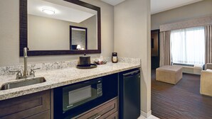 A hotel bathroom with a sink, mirror, microwave, and a coffee maker.