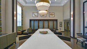 A conference room with a long table, chairs, a decorative centerpiece, and a modern chandelier.