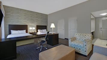Une chambre d’hôtel comprenant un lit, un bureau, une chaise, un pouf et un fauteuil à motifs.