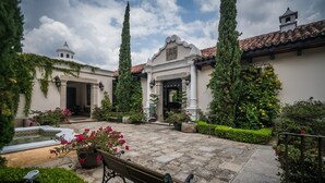 Un patio con una fuente, bancos y plantas en macetas.