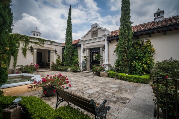 A courtyard with a fountain, benches, and potted plants.