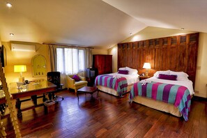 A hotel room with two beds, a desk, a chair, a TV, and a wardrobe.