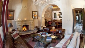 Un salón espacioso con chimenea, muebles de cuero y una araña.