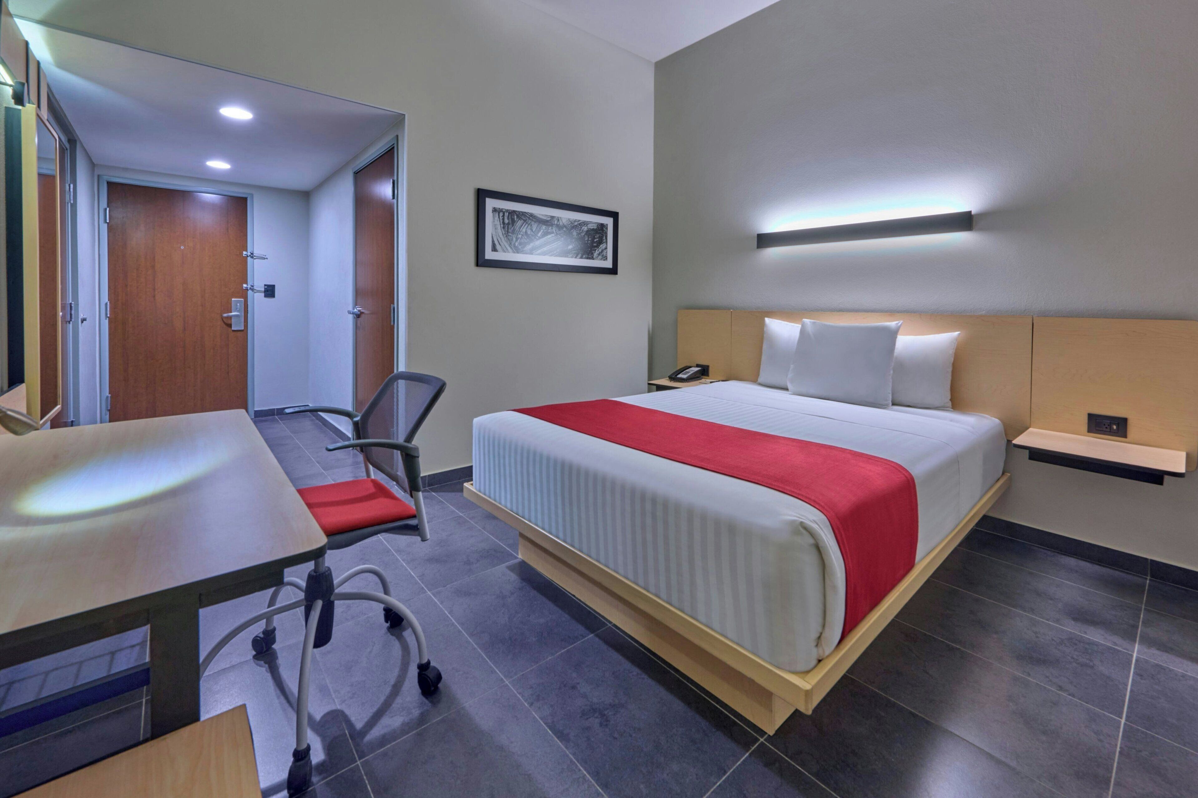Camera d'albergo con un letto, una scrivania, una sedia e un tavolino.