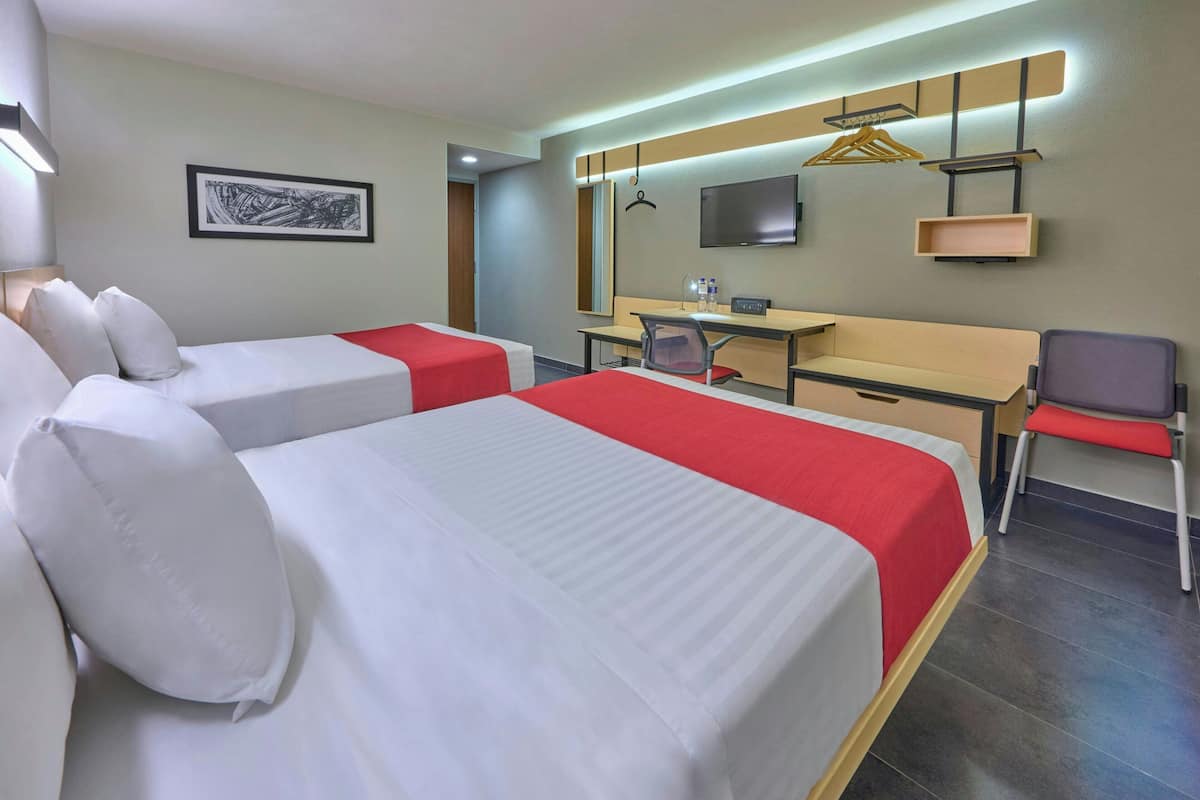 Habitación de hotel con dos camas, un escritorio, una silla, un televisor y un cuadro en la pared.