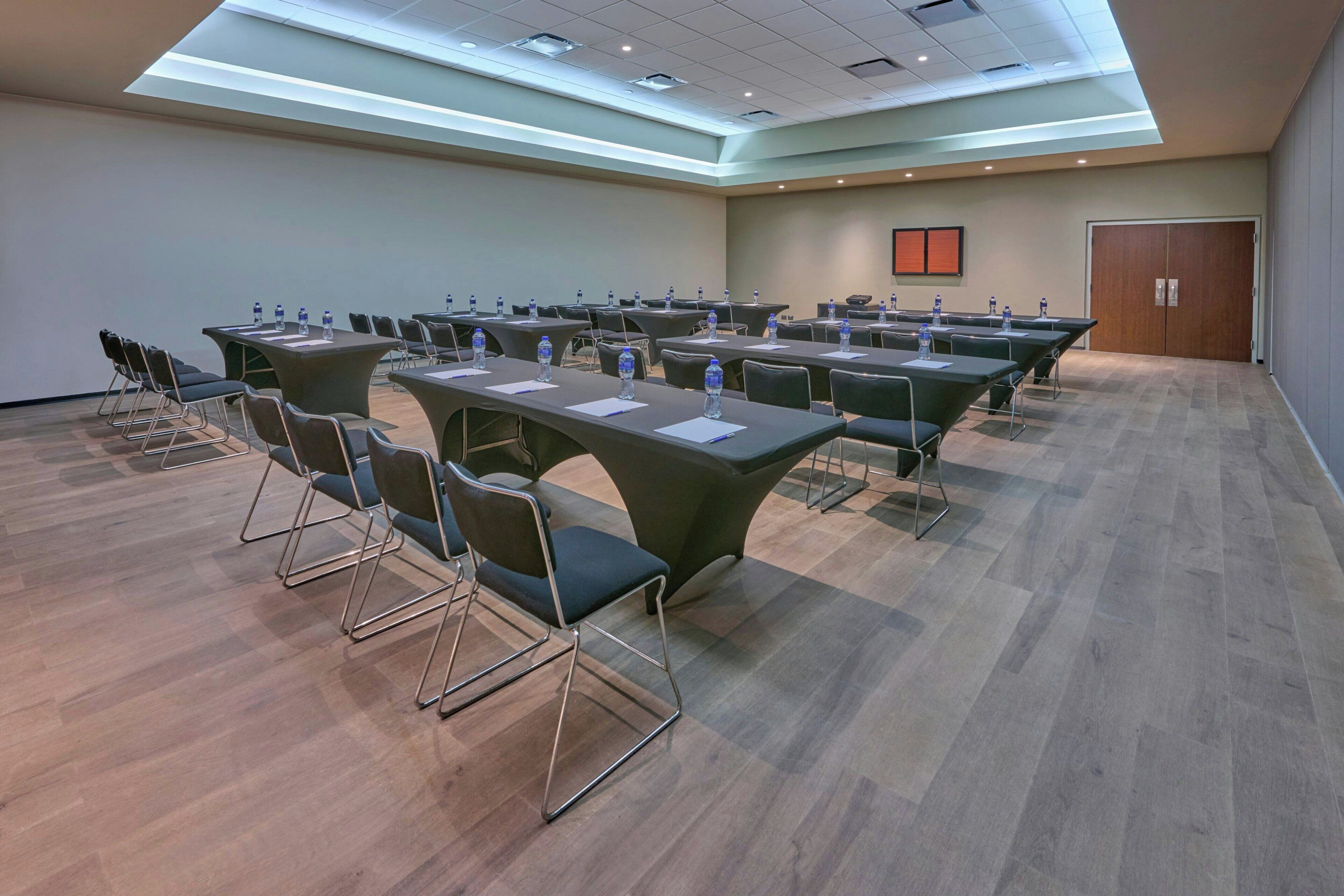 A conference room with long tables, chairs, and water bottles.