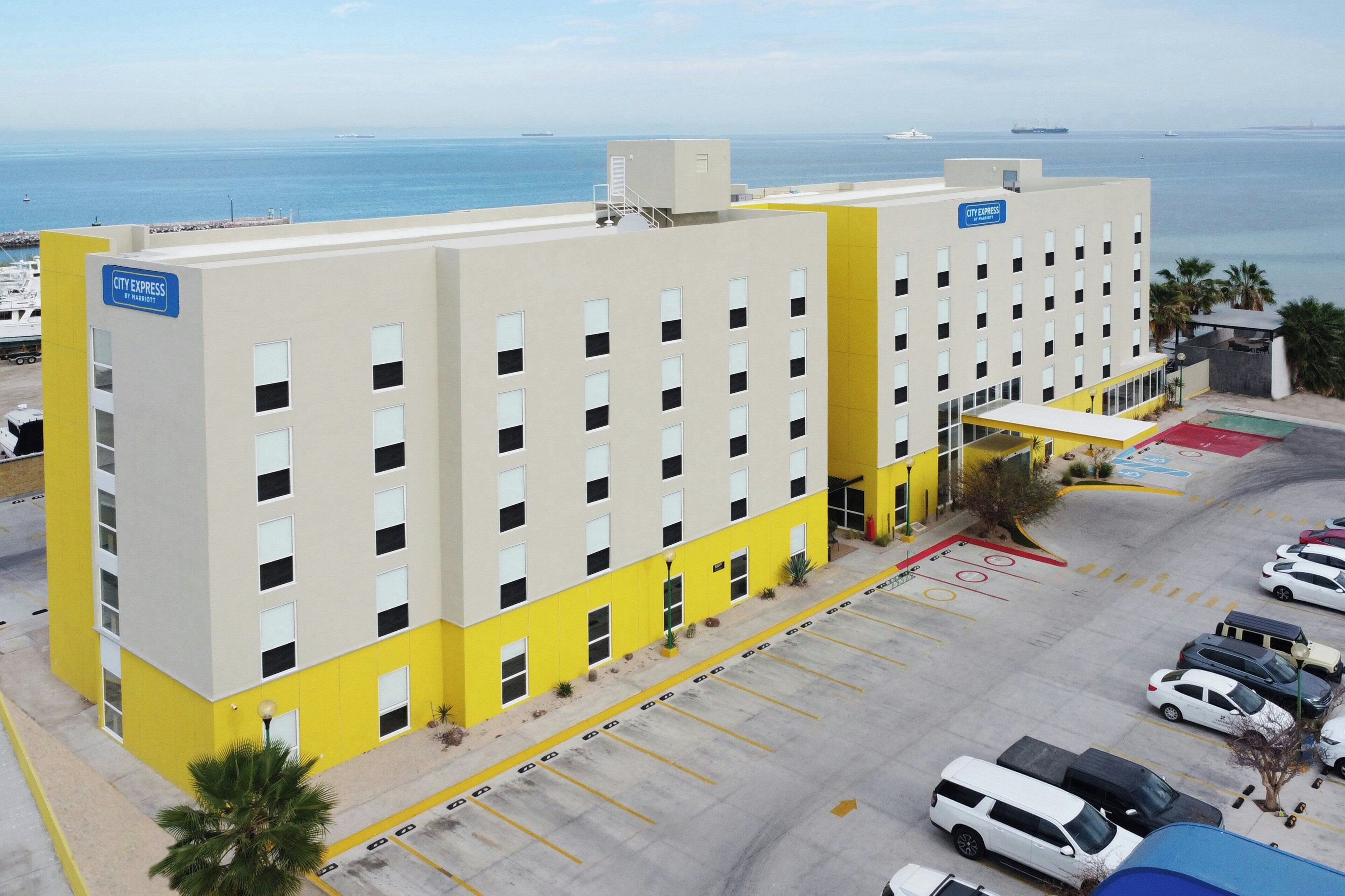 Un hotel con estacionamiento, vista al mar y un letrero de City Express.