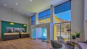 Un'accoglienza moderna con pavimento in legno, una scrivania della reception, ampie finestre che offrono vista sull'esterno e un'area relax con divano e poltrone.